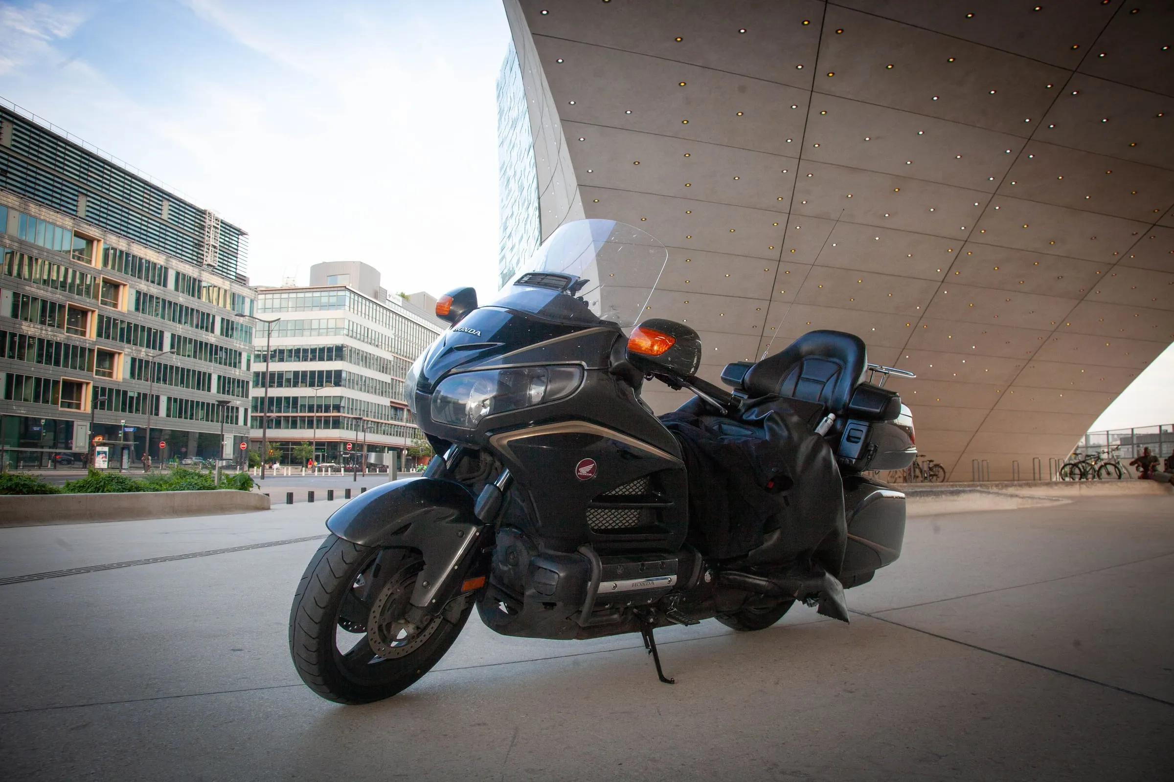 Taxi moto Honda Goldwing en mouvement dans une rue parisienne, voitures à l'arrêt sur la voie de droite