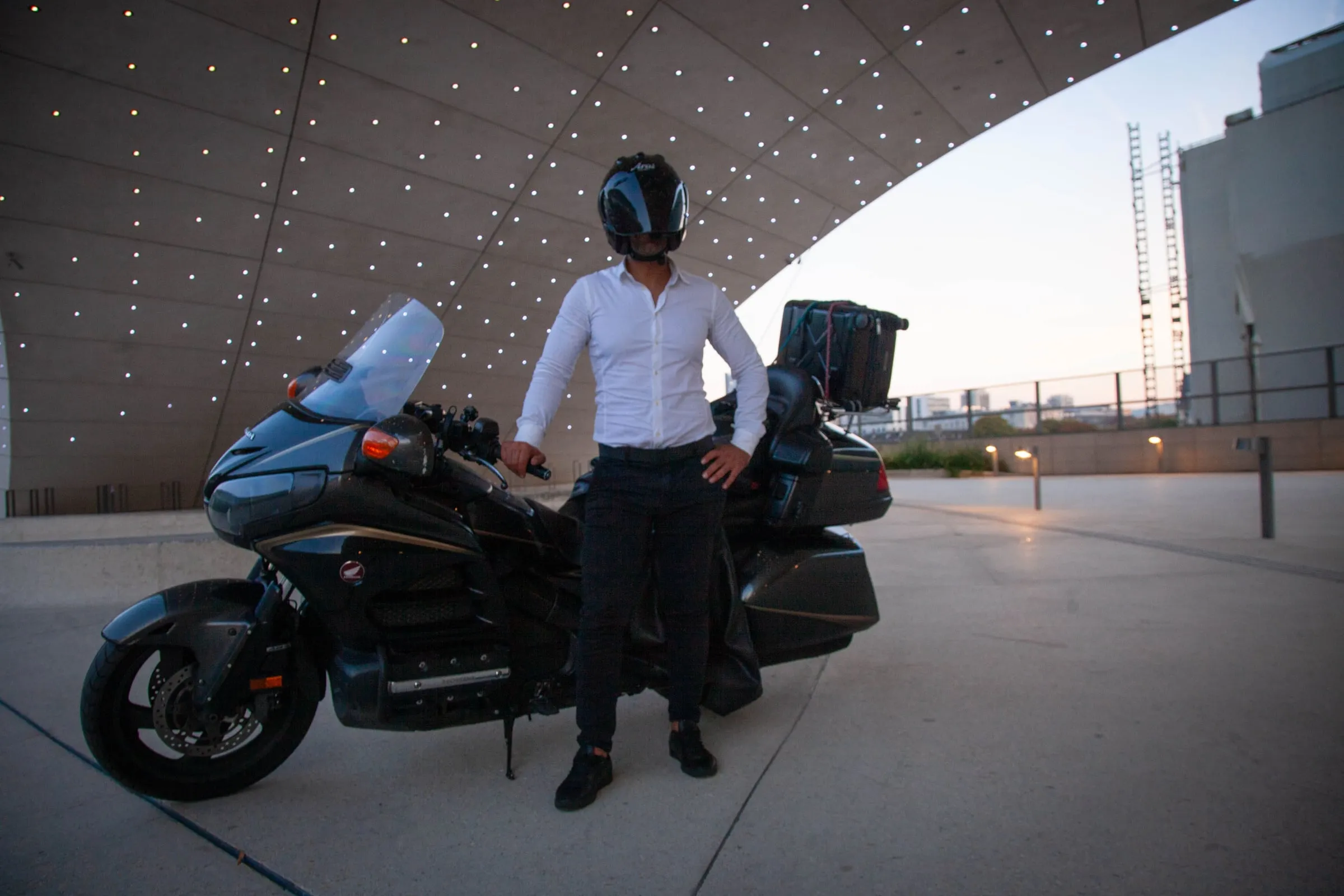 Chauffeur Deluxe Transport en tenue professionnelle à côté de la Honda Goldwing 1800 au crépuscule